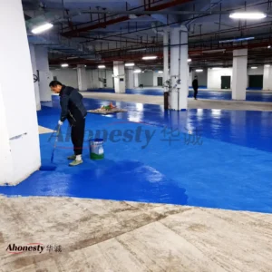 Application of EM45 waterborne polymer anti-slip floor coating in an indoor parking area, showing on-site roller application for durable slip-resistant surfaces.
